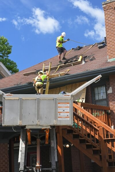 A professional roofing crew adds one layer of shingles to a home's roof.