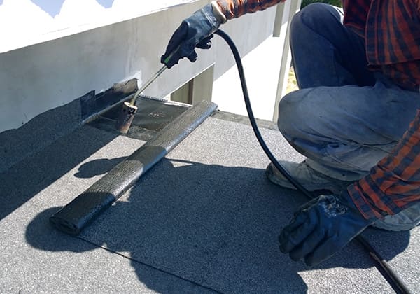 Professional doing roof repair with heat gun 